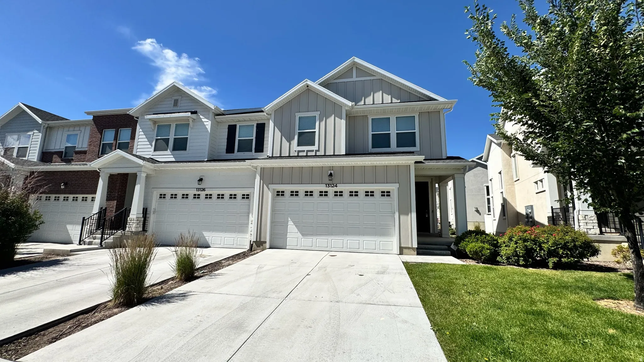 Contemporary townhome exterior featuring light gray siding, white trim, and a two-car garage