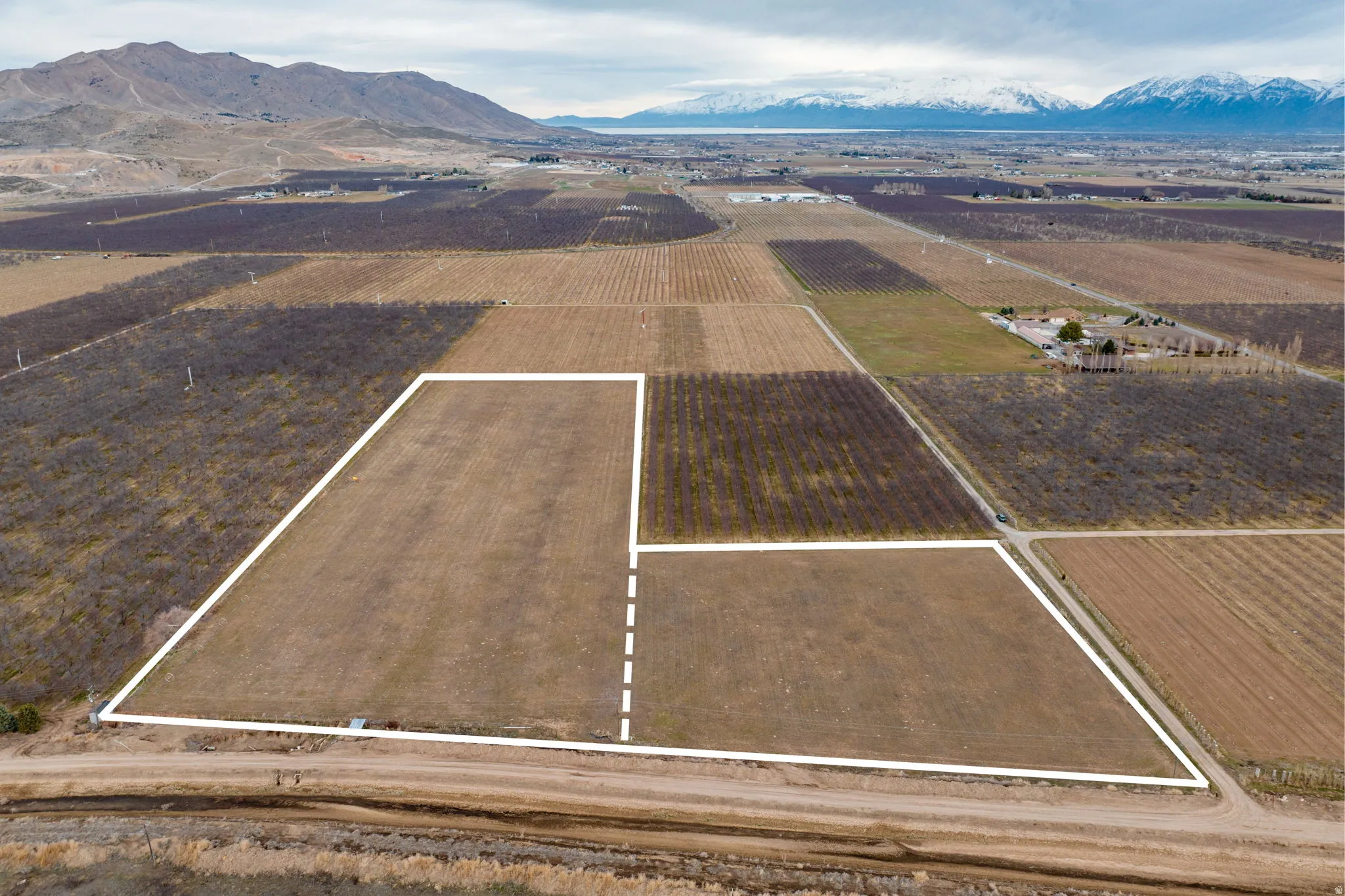 Expansive undeveloped land parcels framed by white boundary lines, featuring diverse terrain including tilled fields and natural vegetation