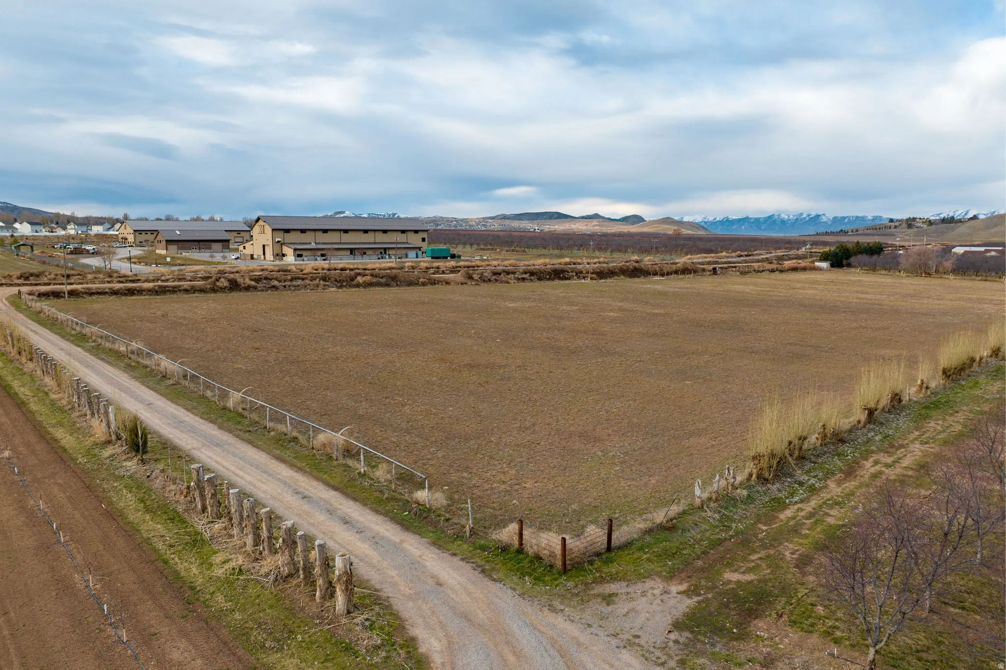 Expansive undeveloped land with a gravel access road and multiple fencing types