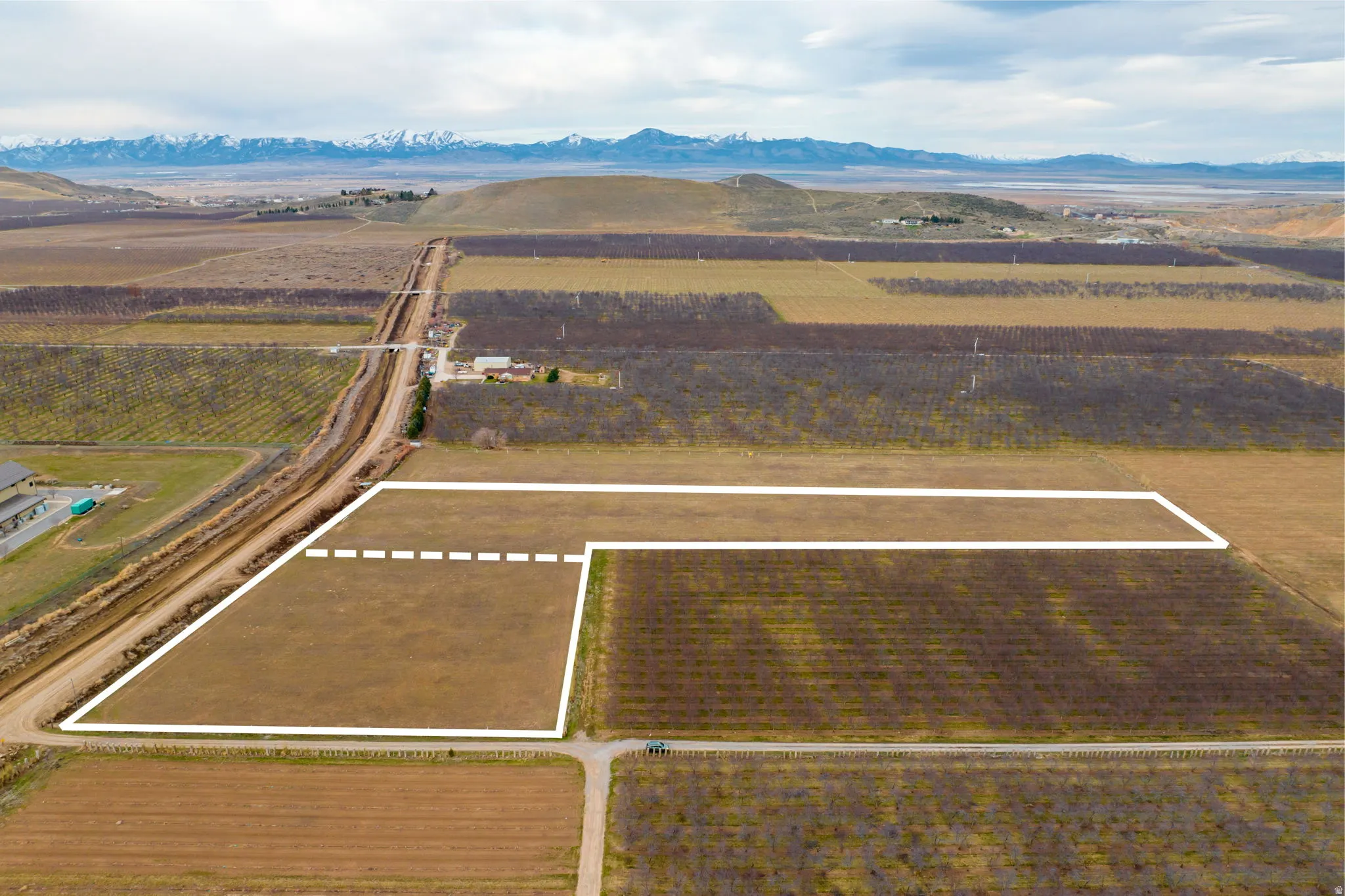 Expansive agricultural land featuring a defined perimeter, surrounding cultivated fields, and distant mountain ranges
