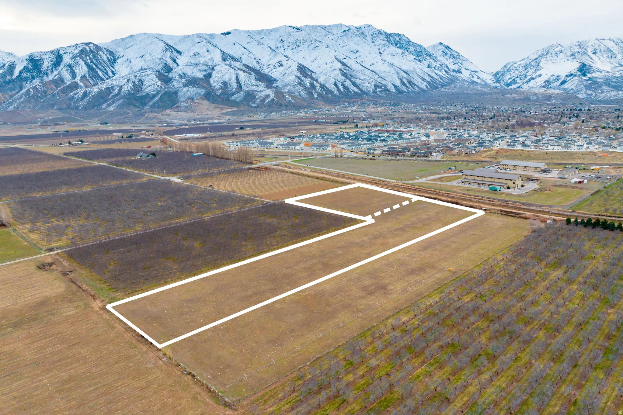 Expansive agricultural land featuring a mountainous backdrop and visible boundary lines