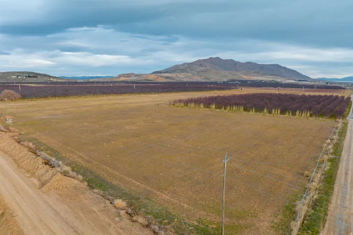 Expansive open field with surrounding agricultural land and distant mountainous terrain