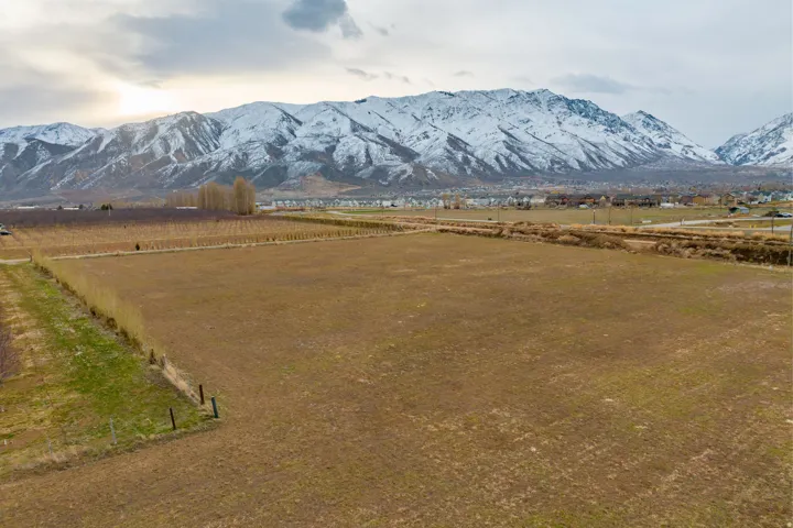 Expansive land parcel featuring clear, level terrain and a backdrop of snow-capped mountains
