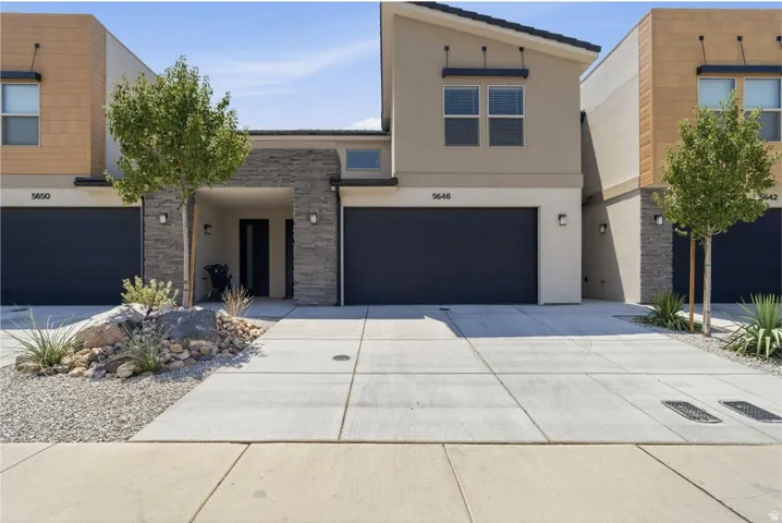 Modern stucco and stone-clad exterior with a dark garage door