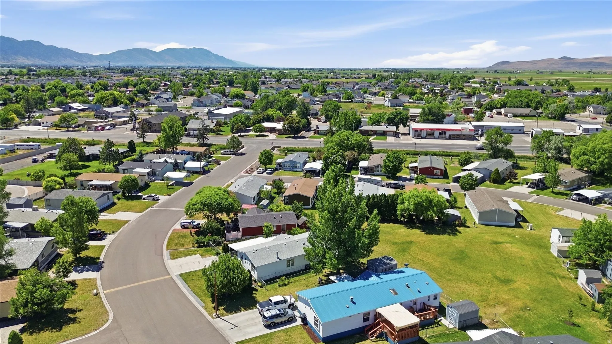 Residential community featuring mature trees, paved streets, and a mountainous backdrop