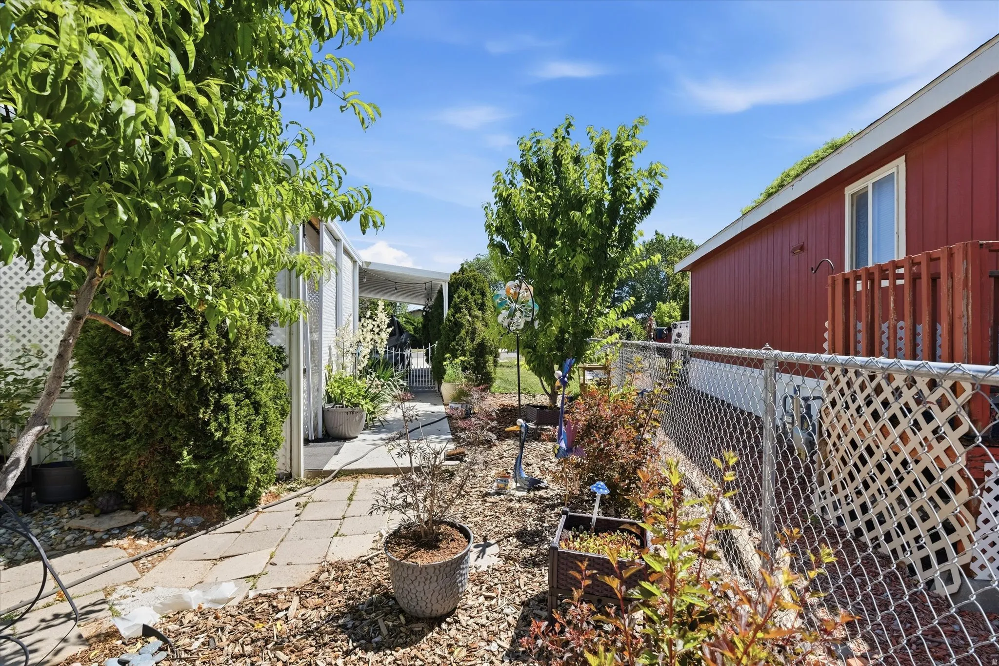Side yard featuring a paver pathway, mature trees, and established plantings