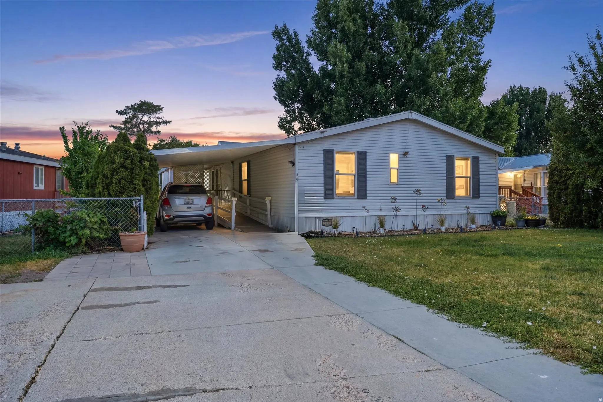 Single-story residence featuring siding with dark window shutters, a covered carport, and an accessible ramp