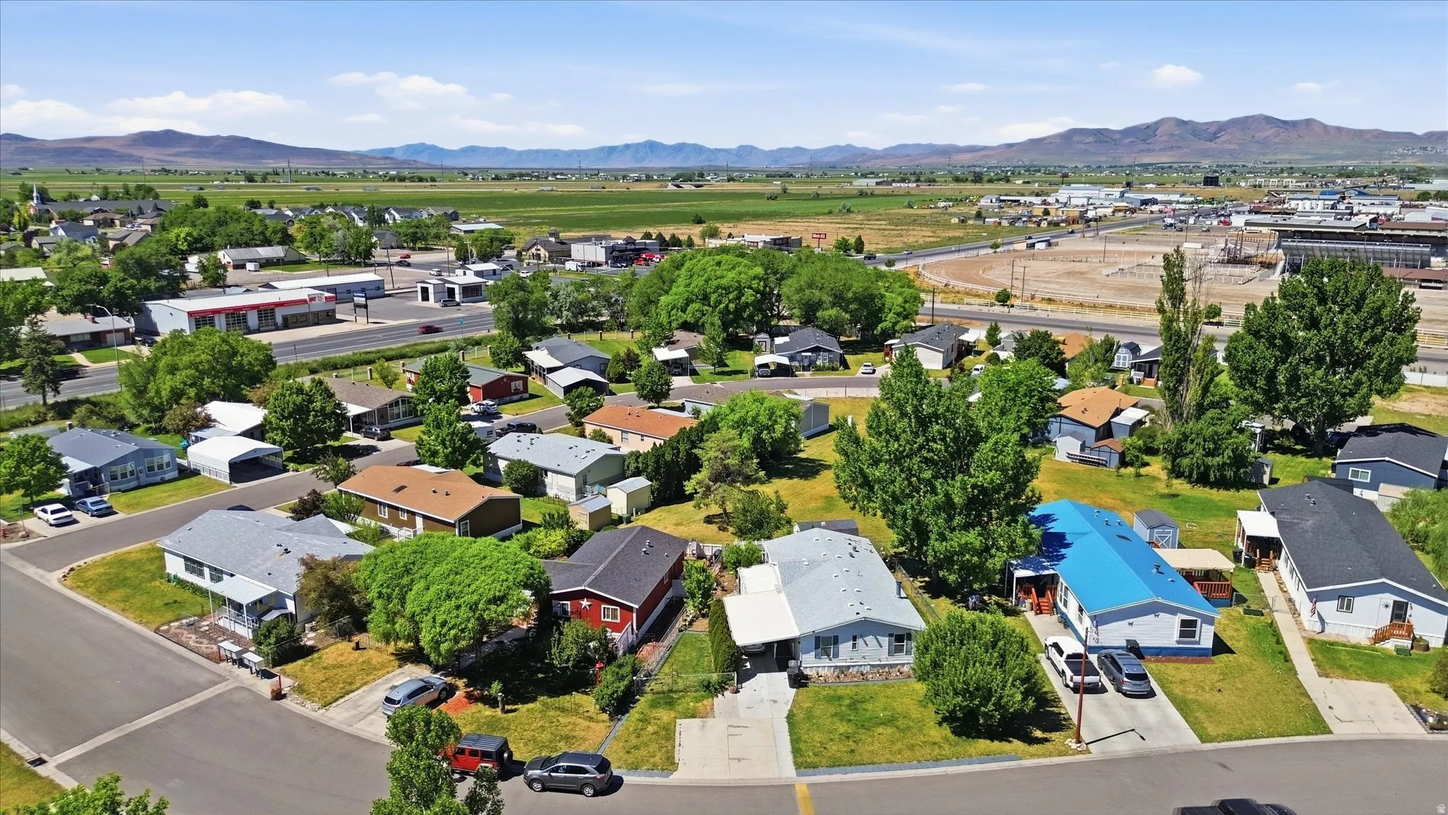 Residential neighborhood featuring established homes, mature trees, paved streets, and framed by distant mountains
