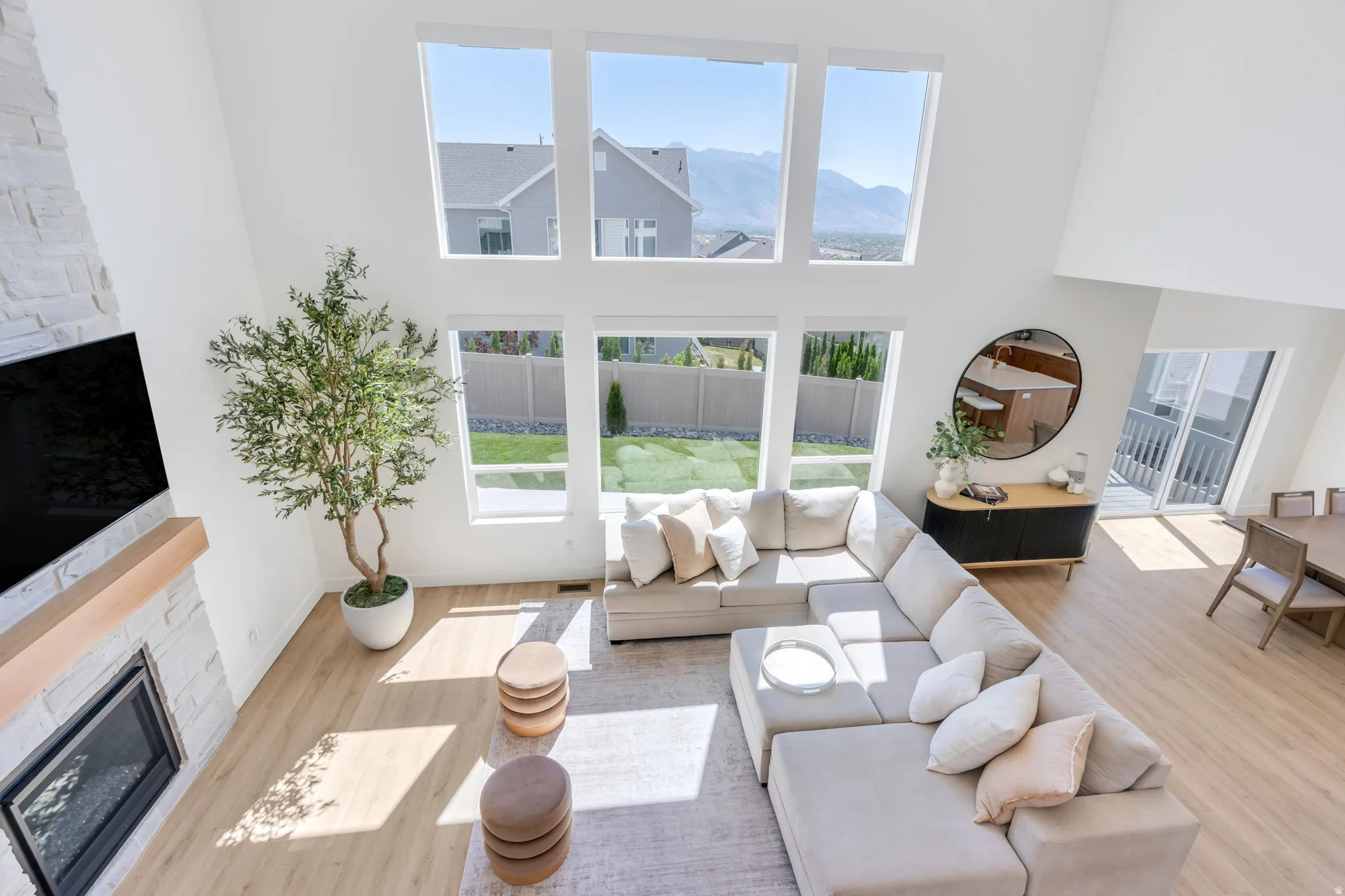 Living space featuring a two-story ceiling, a fireplace with a light-toned stone surround, a wood mantel, and expansive windows