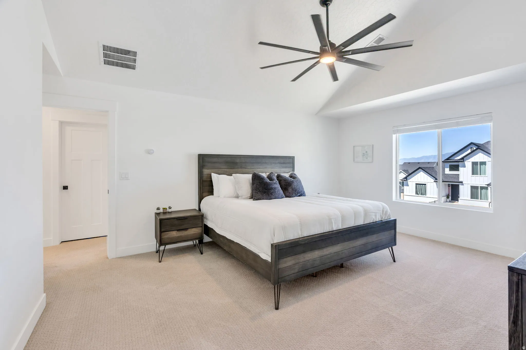 Spacious room featuring vaulted ceilings, a contemporary ceiling fan, and carpeted flooring