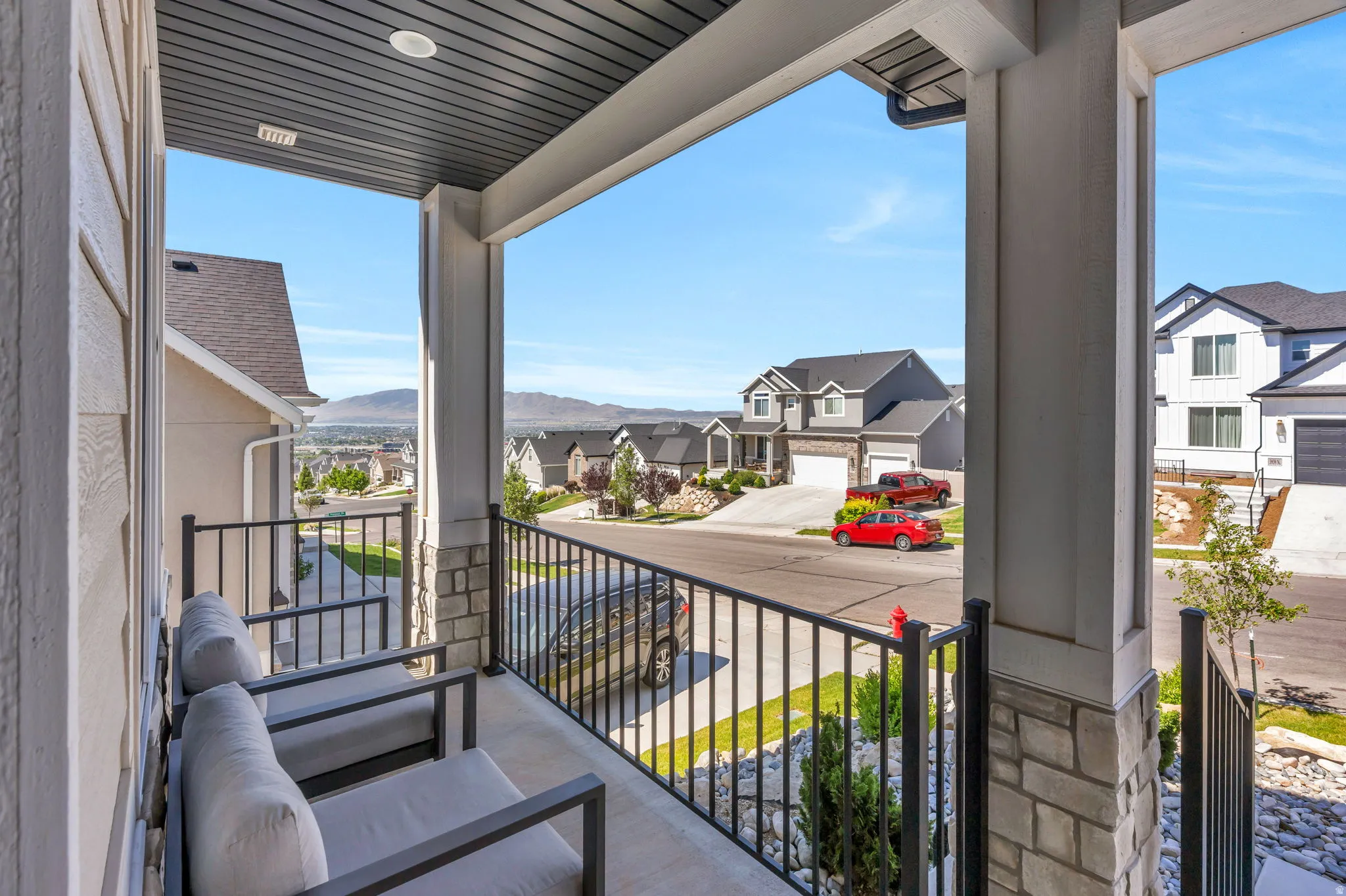 Covered front porch featuring a dark slatted ceiling, recessed lighting, and stone column bases