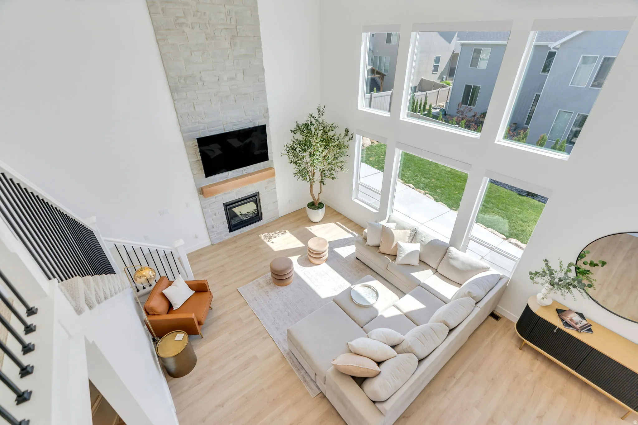 Vaulted ceilings featuring a floor-to-ceiling stone-surround fireplace with a wood mantel