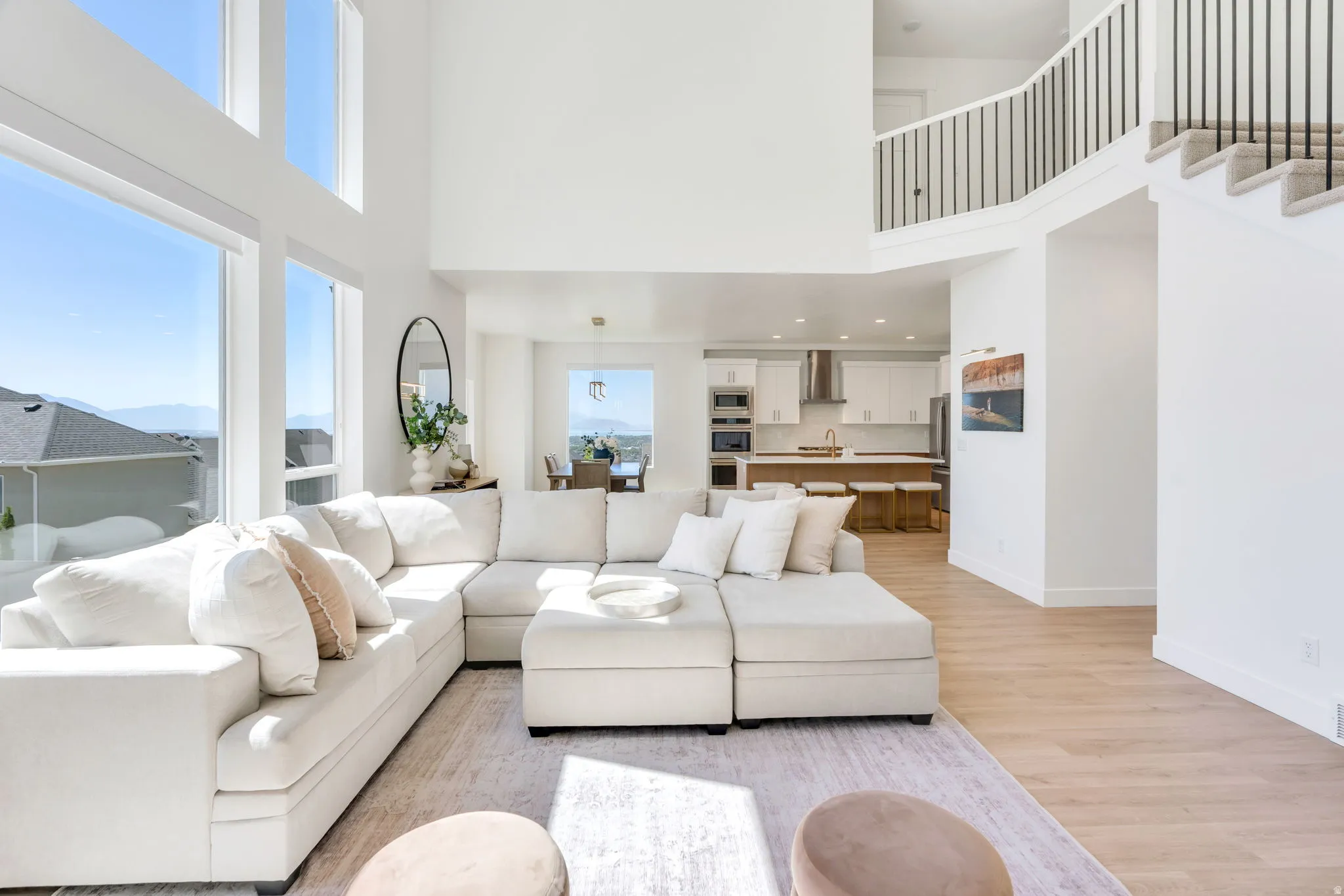 Two-story living area with expansive windows, light wood-finish flooring, and a second-level open railing