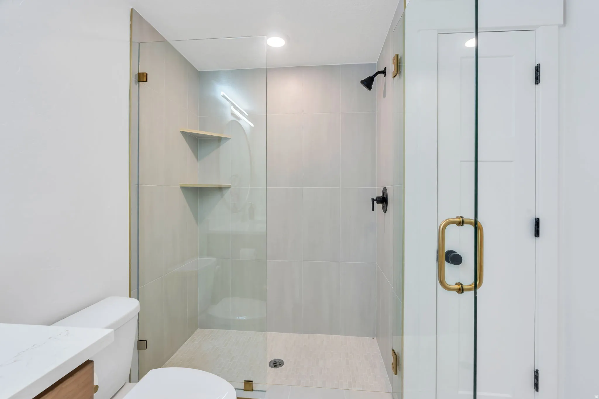Modern shower enclosure featuring clear glass panels with brass hardware