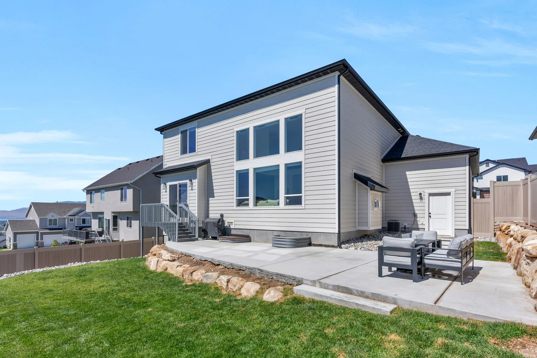 Rear exterior featuring light-colored siding, a multi-pane window configuration, and a concrete patio