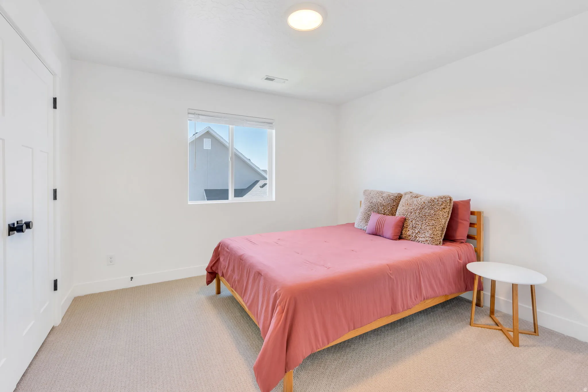 Carpeted room with a single window and white walls