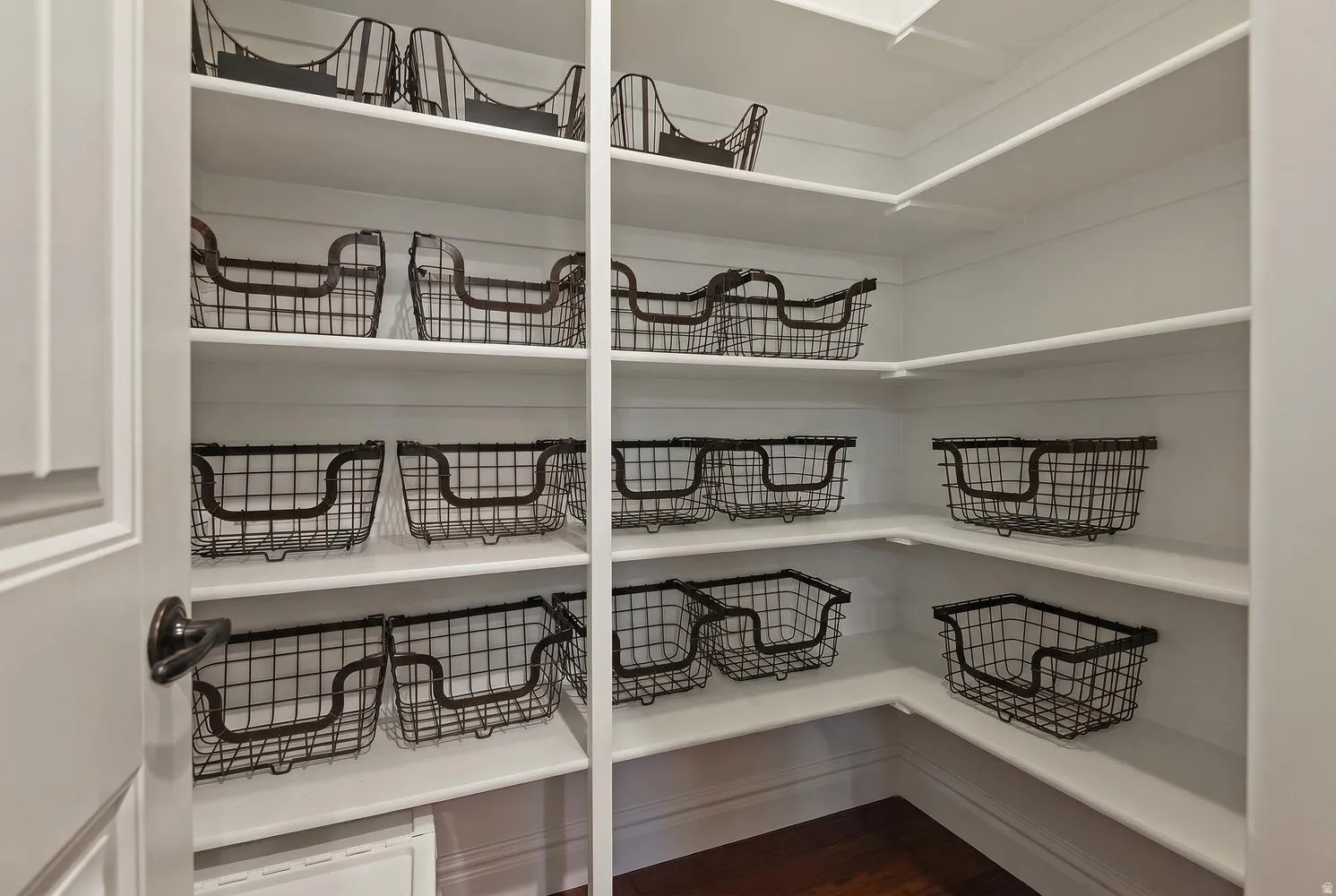 Walk-in pantry featuring white shelving, shiplap-style wall paneling, and dark wood-finish flooring