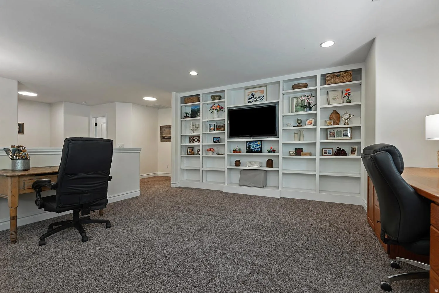 Integrated media wall with built-in shelving, recessed lighting, and soft carpet flooring