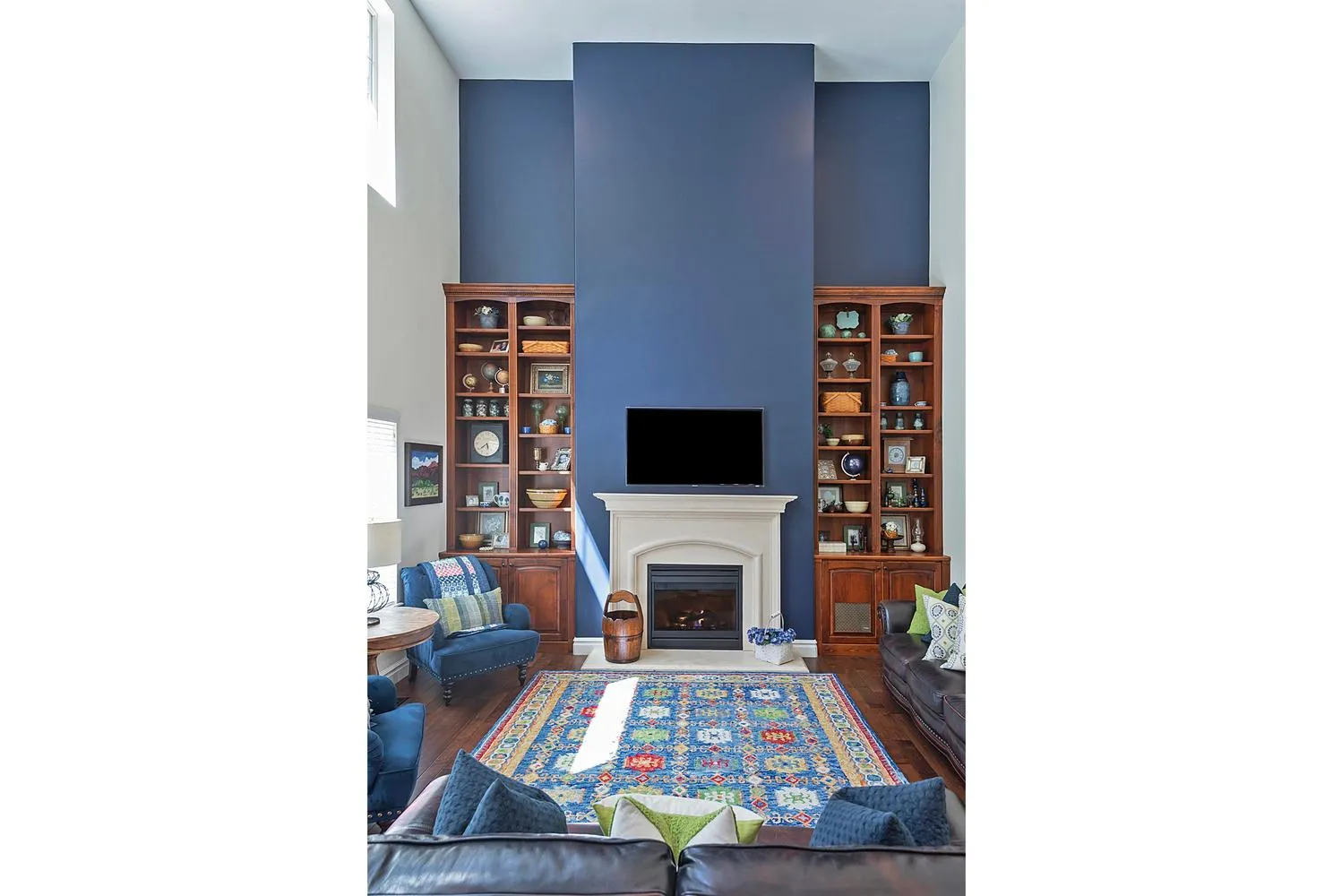 Living area featuring a floor-to-ceiling accent wall, a stone-surround fireplace, and wood-finish flooring