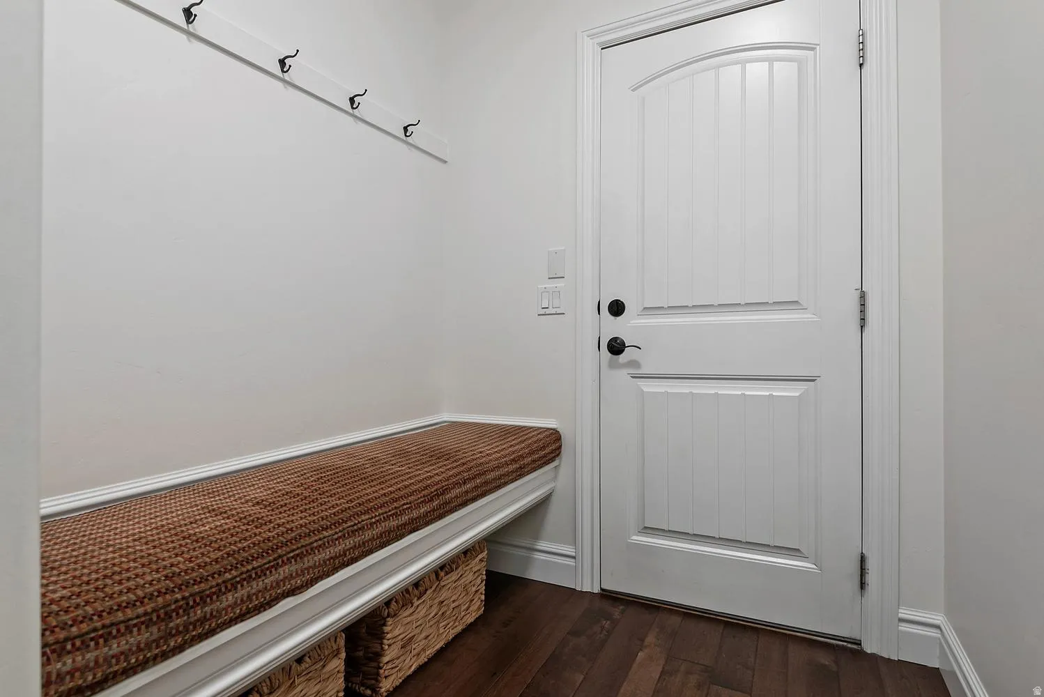 Entryway mudroom featuring a built-in bench with storage, wood-finish flooring, and a paneled door