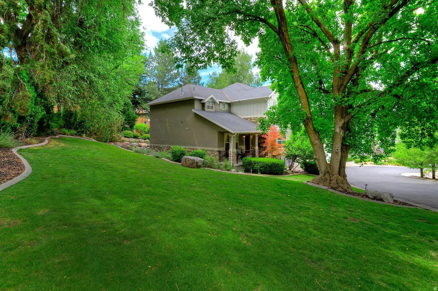 Expansive green lawn with mature trees and landscaped planting beds