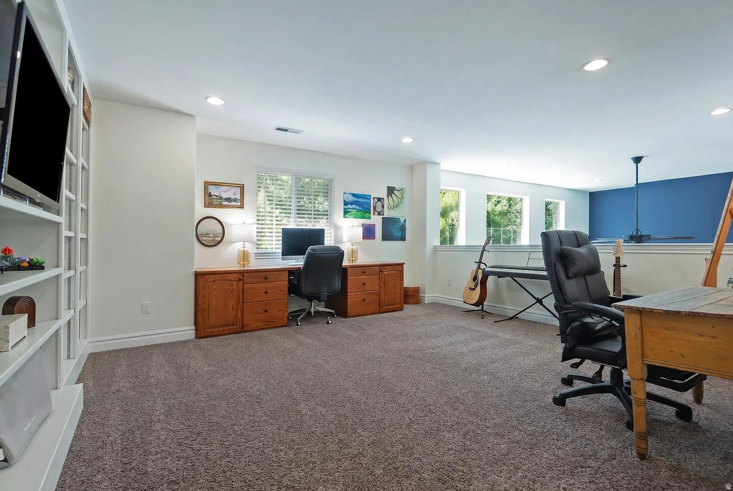 Spacious room featuring a built-in white shelving unit, recessed lighting, and ample natural light from multiple windows