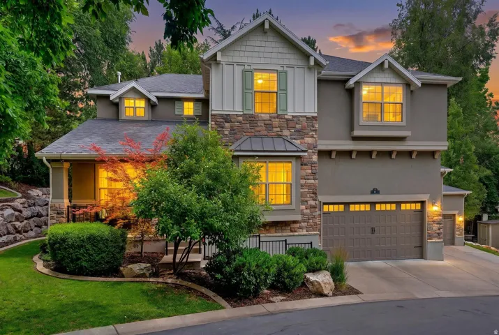 Multi-level residence featuring a stone and stucco exterior, prominent bay window, attached two-car garage, and a concrete driveway