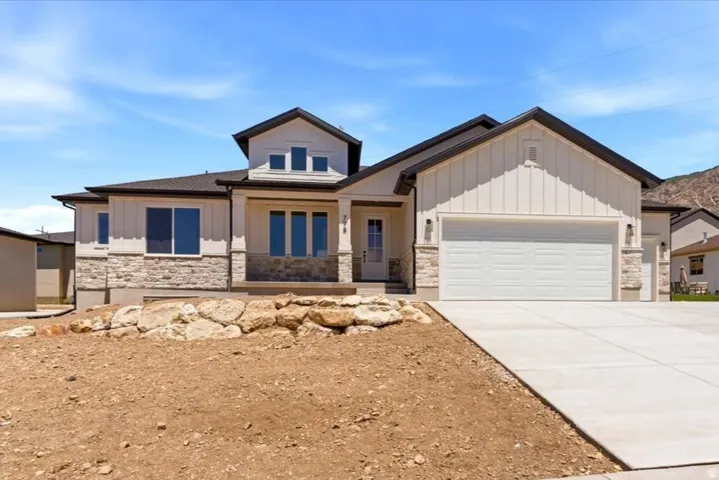 Modern farmhouse-inspired exterior with  board and batten siding, stone facade accents, dark trim, and an attached two-car garage