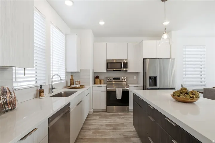 Bright, open kitchen featuring quartz countertops, stainless steel appliances, a large island, and contemporary finishes in this Daybreak townhome.