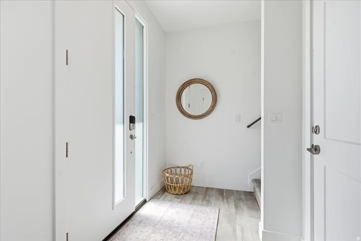 Entryway featuring light wood-finish flooring, a contemporary white door with frosted glass, and a modern deadbolt
