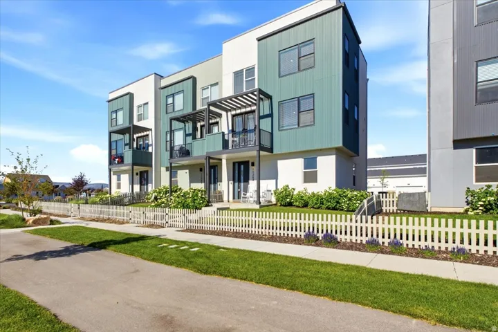 Contemporary end-unit townhome with a fenced front yard and modern architectural design.
