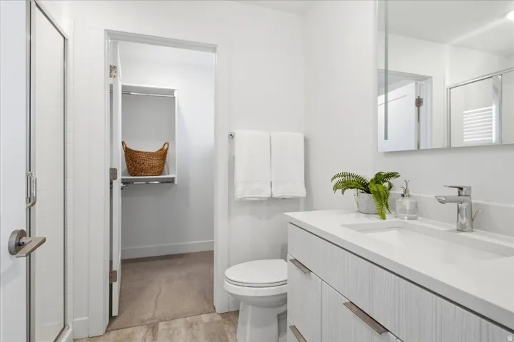 Primary bathroom featuring a quartz vanity, contemporary fixtures, and a spacious layout.