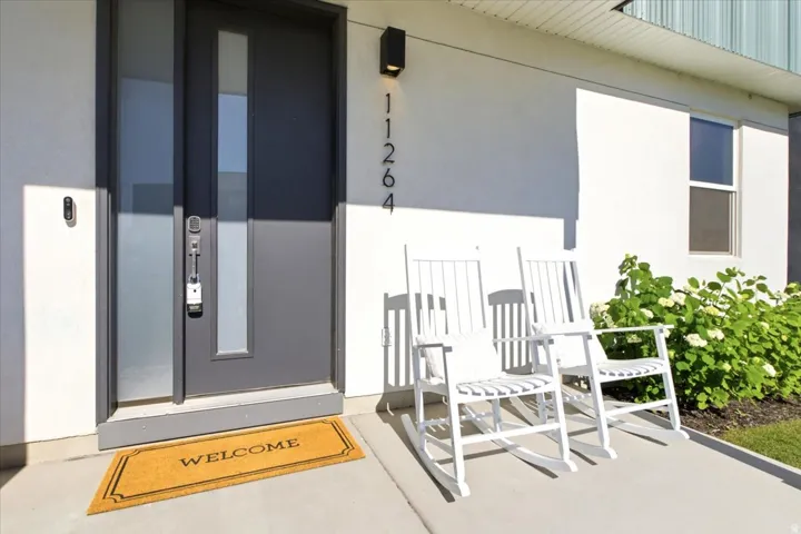 Contemporary gray entry door with frosted sidelight, wall-mounted light fixture, and digital doorbell