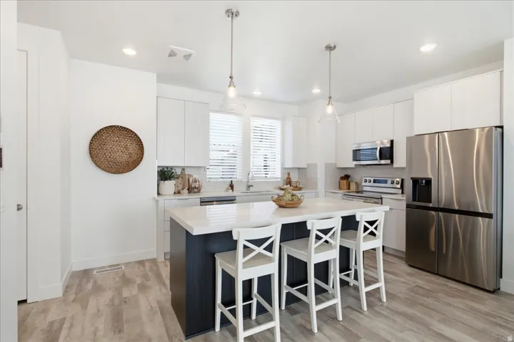 Modern kitchen with quartz countertops, oversized island, stainless steel appliances, and abundant cabinetry.