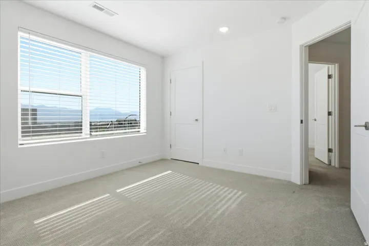 Bright secondary bedroom with expansive windows, mountain views, and generous natural light.