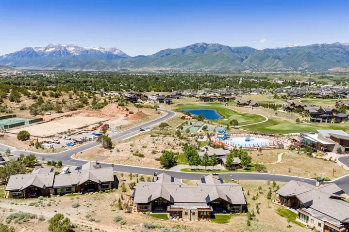 Expansive community featuring multiple residential structures, a golf course, and a recreational pool area