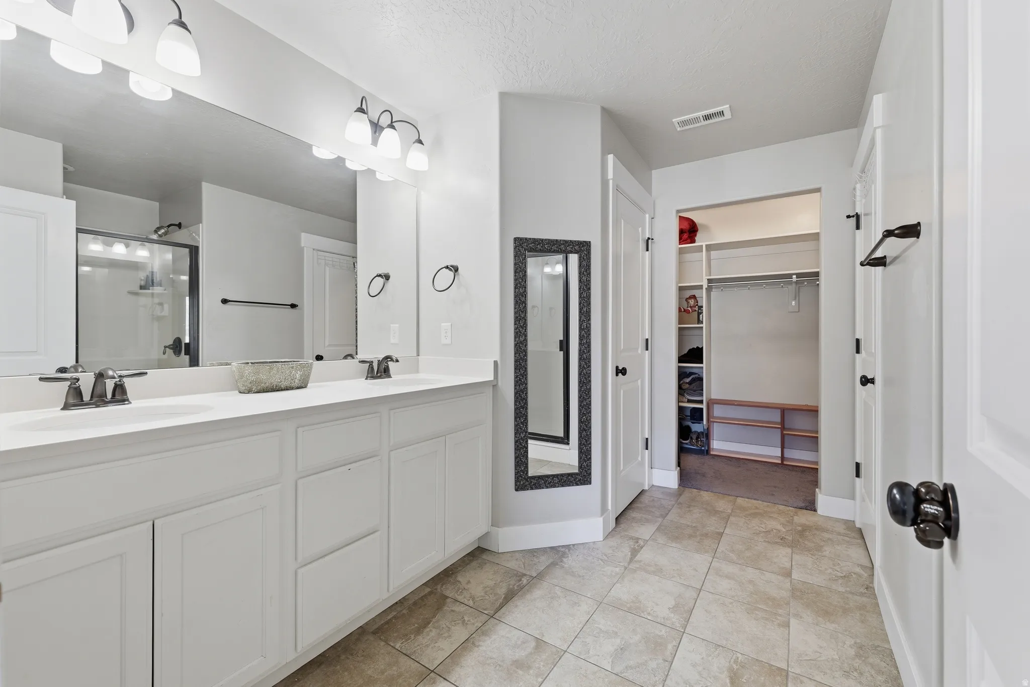 Bathroom featuring a dual vanity with white cabinetry and a light-colored countertop