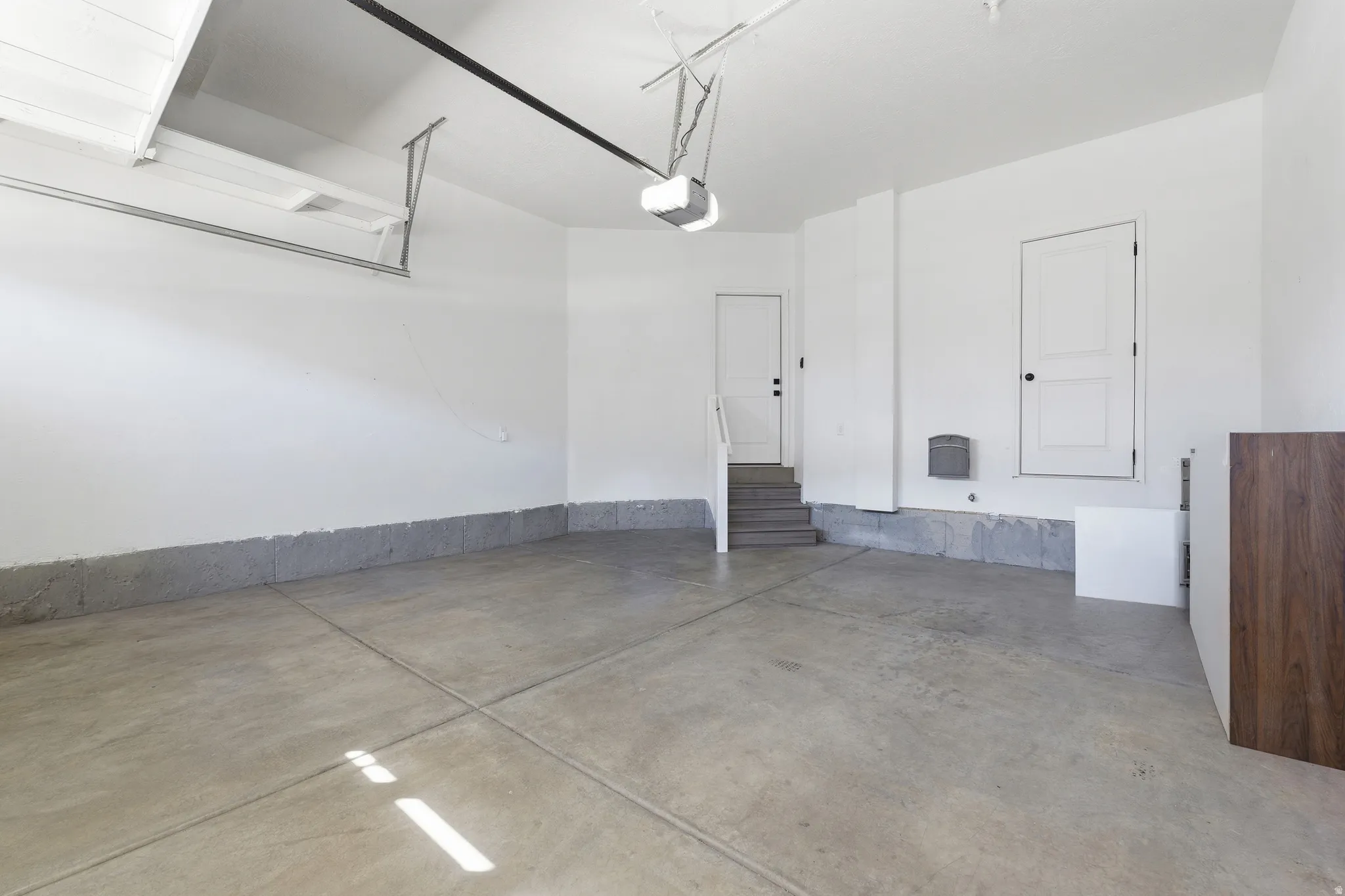 Spacious garage featuring a concrete floor, bright white walls, and a visible garage door mechanism