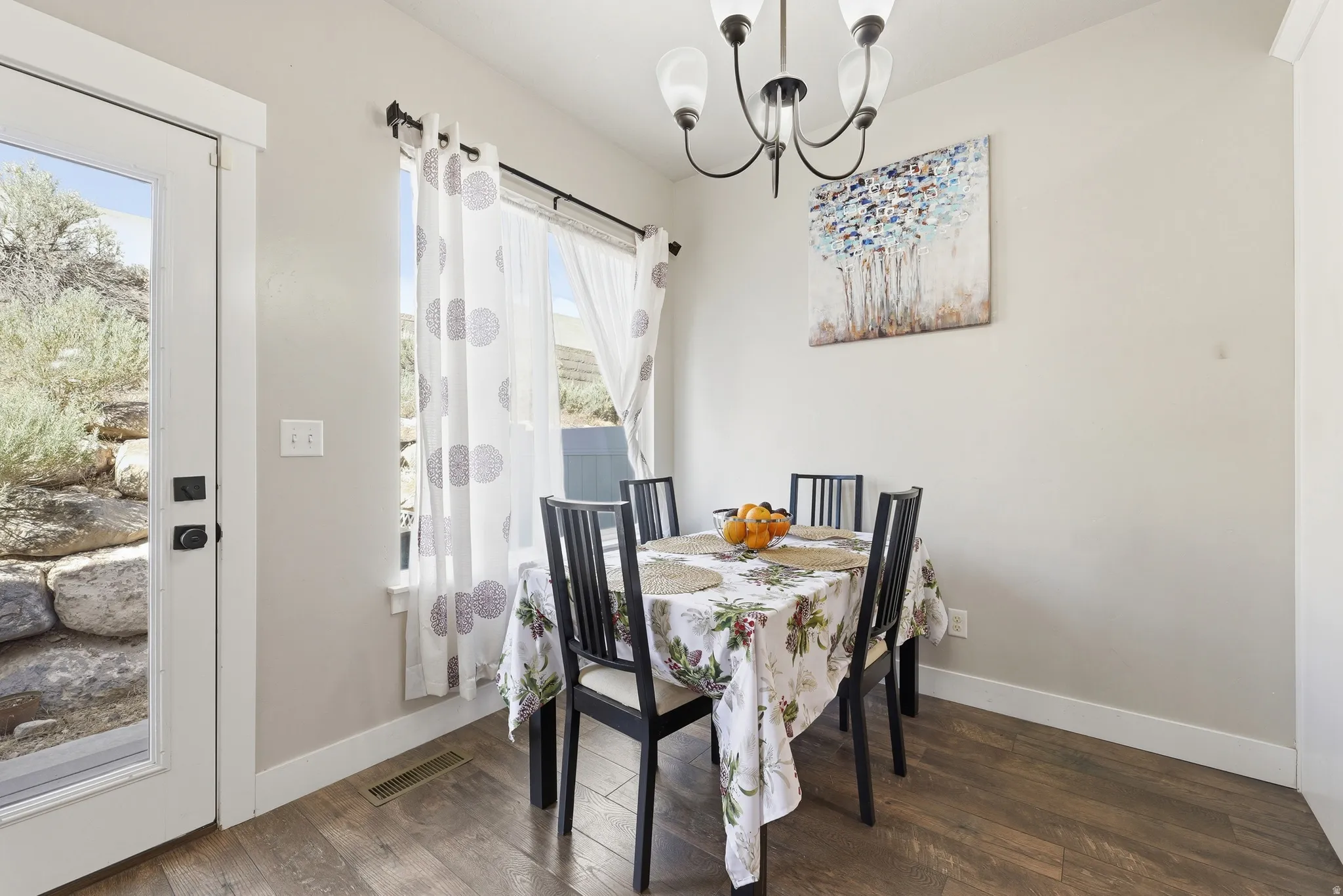 Dining area featuring wood-finish flooring, a contemporary chandelier, and a glass-paneled exterior door