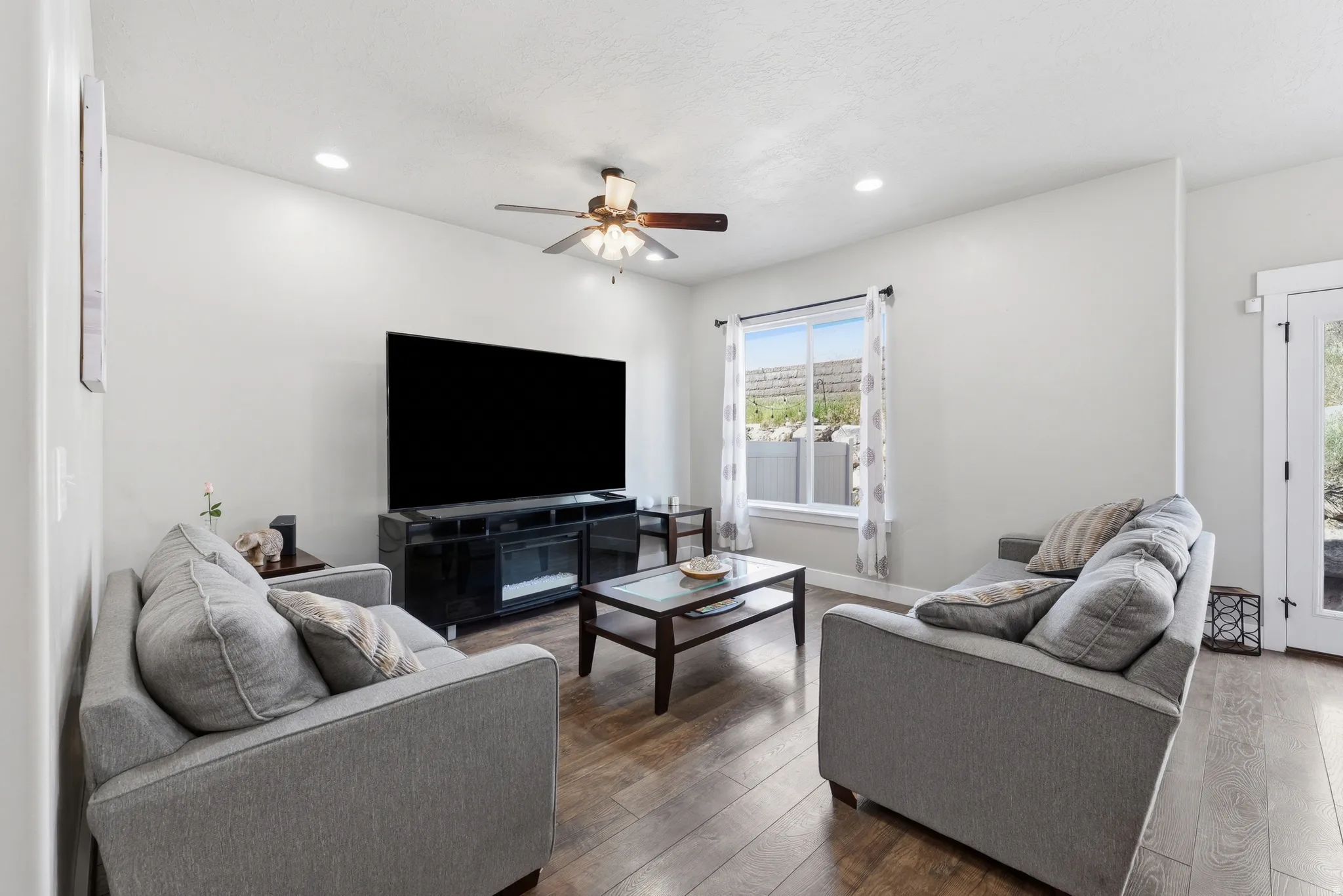 Spacious living area featuring wood-finish flooring, recessed lighting, and a ceiling fan