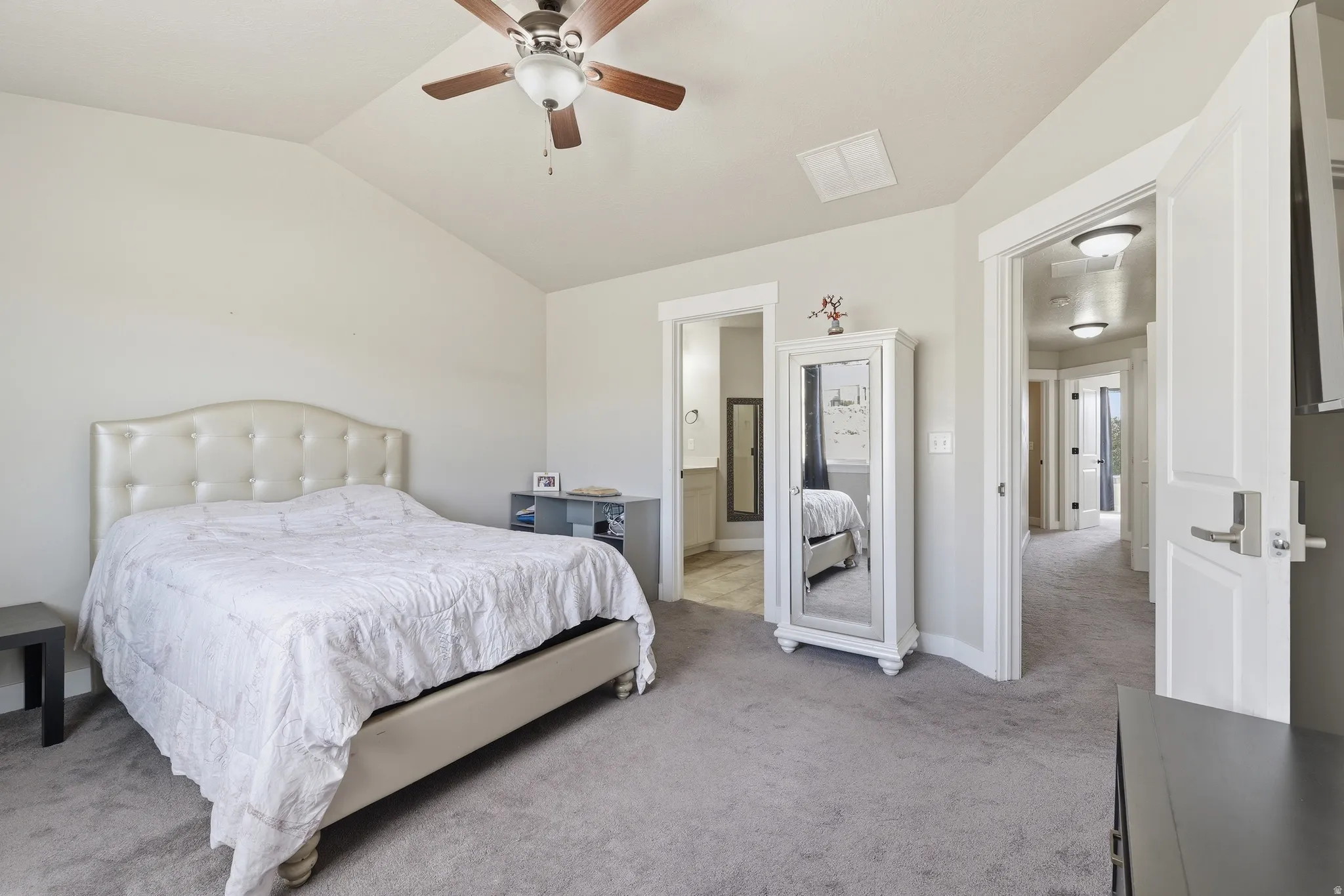 Carpeted room with a vaulted ceiling and a ceiling fan