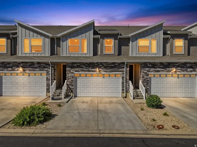 Modern townhome facade featuring a stone veneer, gray siding, and a prominent gable roofline