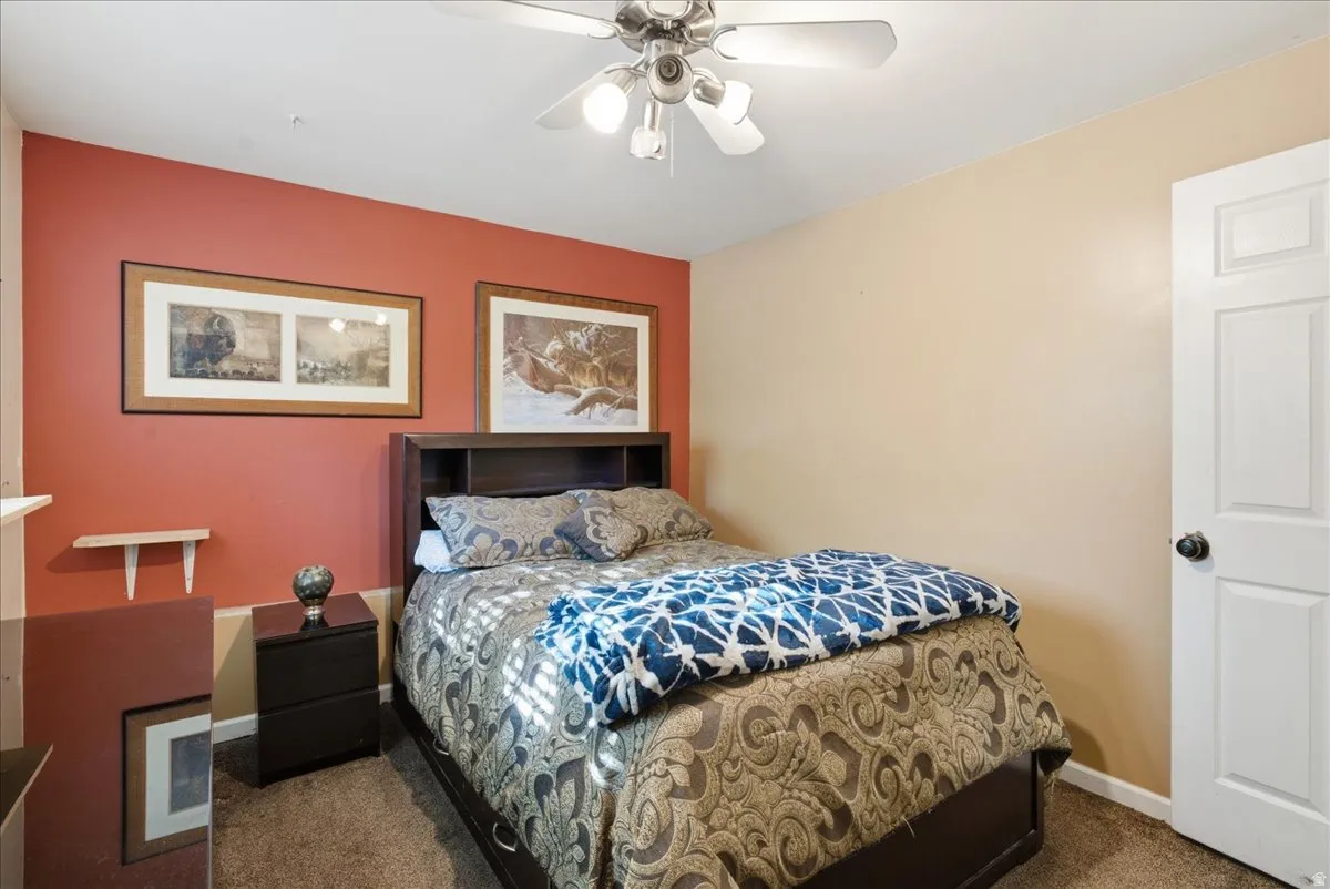 Bedroom featuring a ceiling fan with light fixture, two-panel interior door, and neutral-tone carpeting