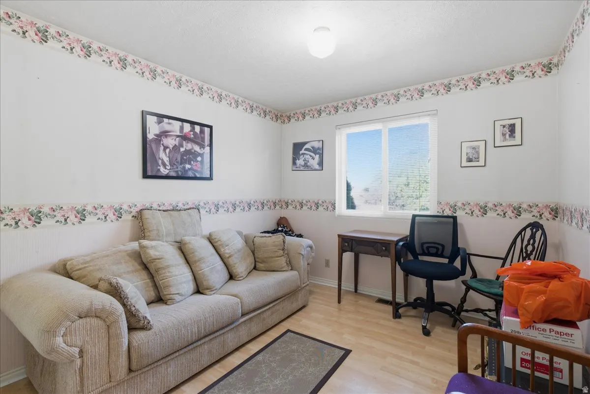 Bright interior space featuring a window with exterior visibility, light wood-finish flooring, and a white ceiling with a flush-mount light fixture