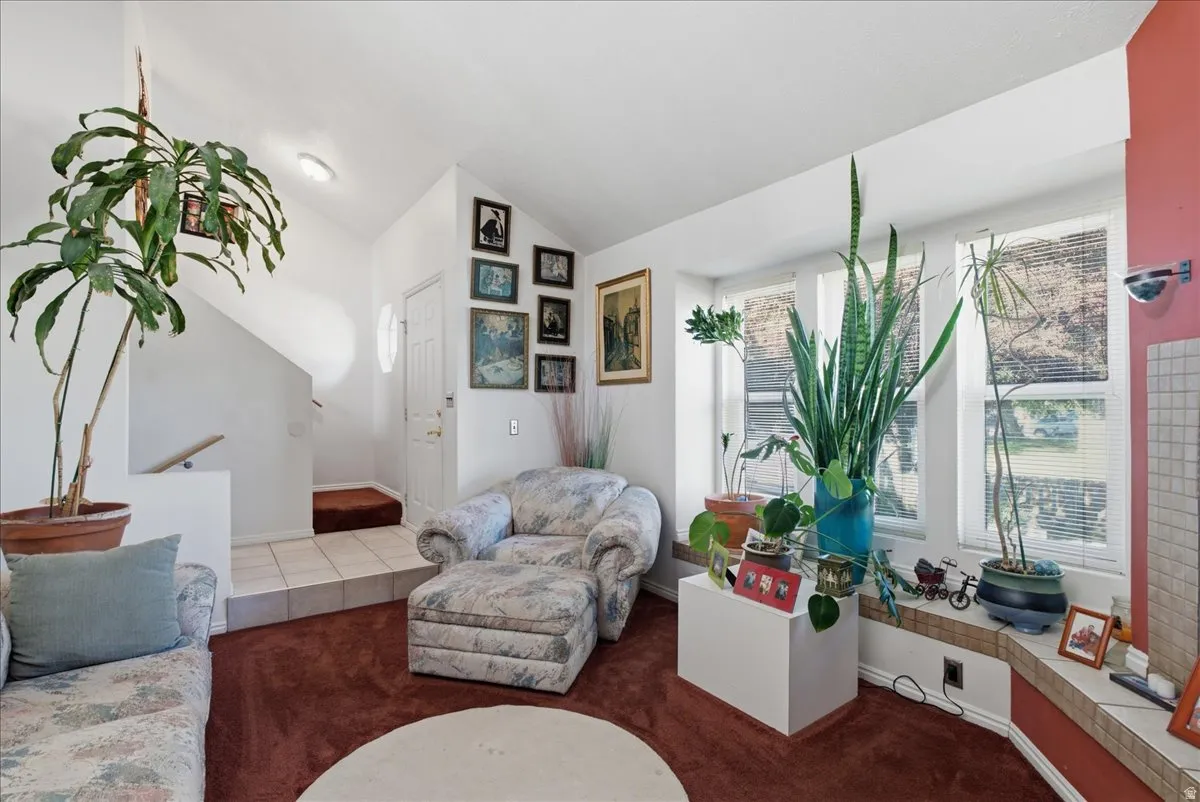 Living area featuring a multi-pane window with a deep sill, a tiled entryway, and a staircase with a wood handrail