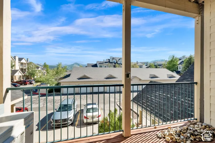 Expansive balcony featuring wood-finish flooring, a metal railing, and broad landscape views