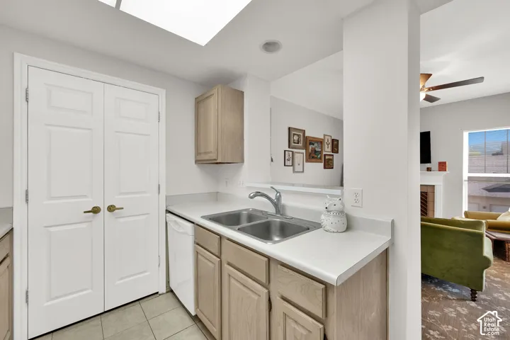 Kitchen featuring a dual basin sink with chrome faucet, light wood-finish cabinetry, and white countertops