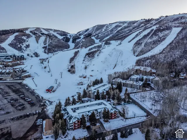 Aerial perspective showcasing multiple properties nestled at the base of a snow-covered mountain with defined ski runs