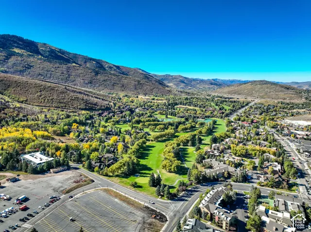 Expansive aerial perspective showcasing a mountainous terrain, a verdant golf course, and a residential area