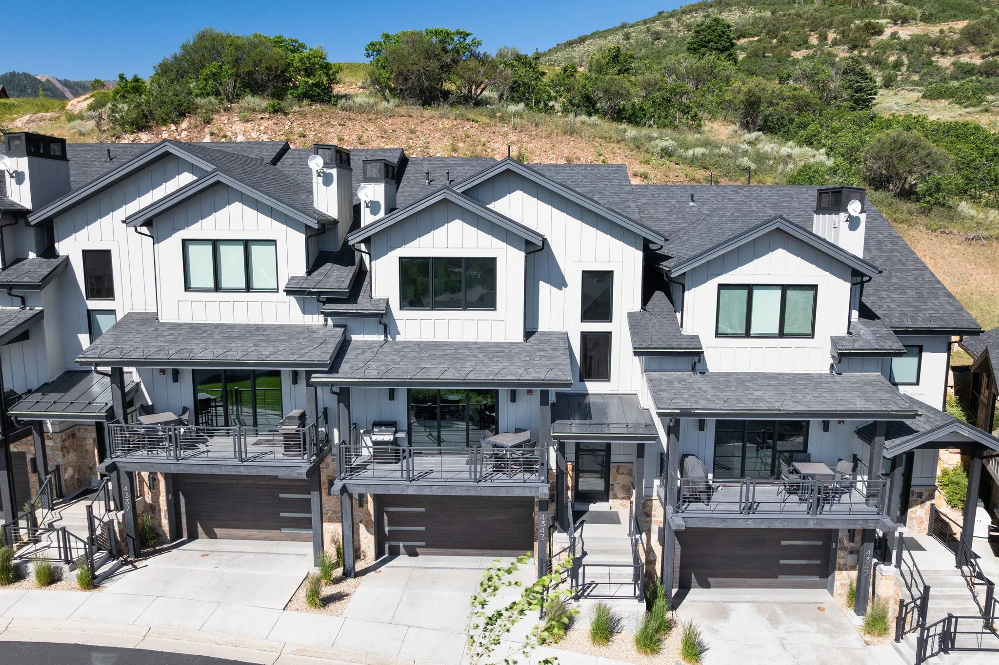 Modern townhome exteriors featuring vertical and horizontal siding, dark-framed windows, and private balconies with black railings